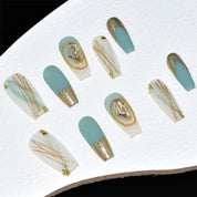 Set of long, coffin-shaped press-on nails in matte aqua blue and glossy beige with gold accents, including glitter and geode patterns.