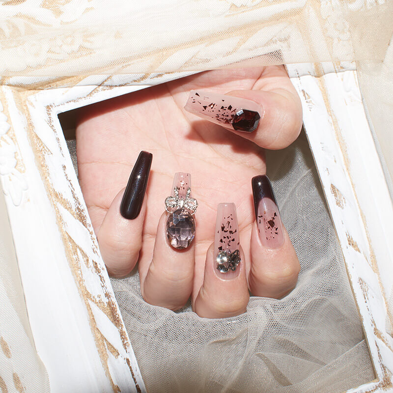 Hand showcasing burgundy blush press-on nails with elegant designs and sparkling accents